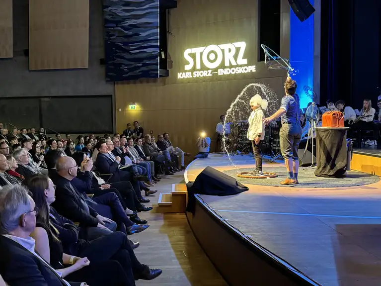 Performer creating a large soap bubble around a child on stage at a corporate event.