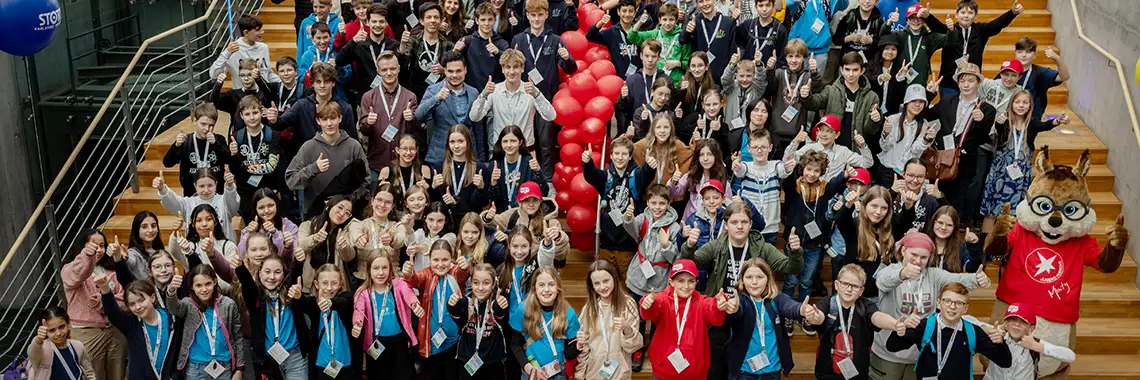 A large group of people gathered on stairs, many showing thumbs up and wearing name badges.