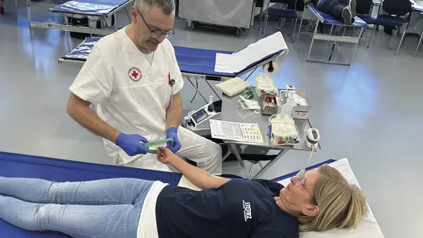 Medical professional prepares woman for blood donation in clinic on a reclining bed.