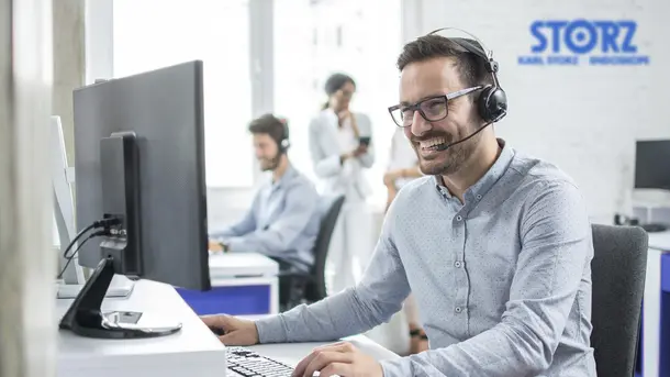 Man wearing headset working at computer in a modern office environment.