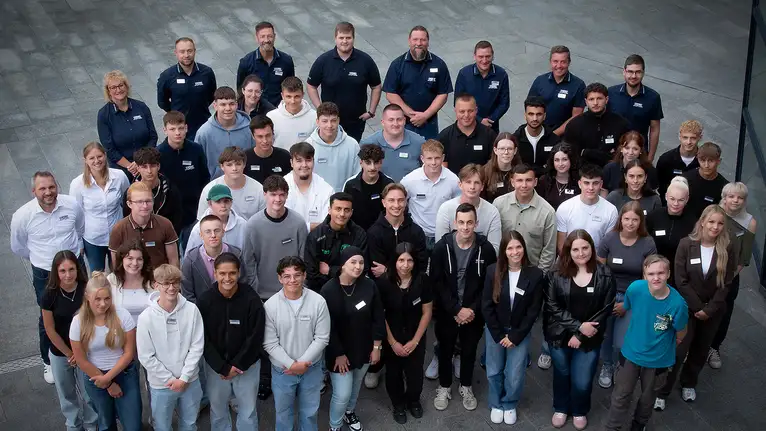 Gruppenfoto von mehreren Menschen, größtenteils junge Erwachsene, stehend in Reihen für ein gemeinsames Bild.