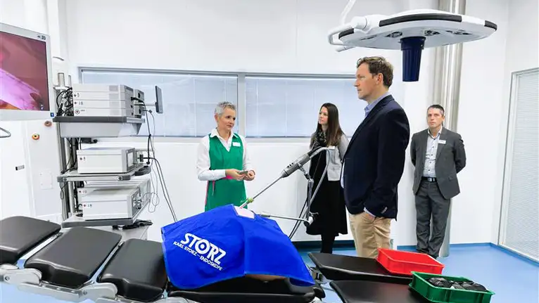 Medical staff and professionals demonstrating surgical equipment in an operating room.