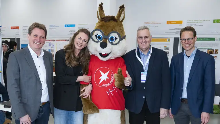 Gruppe steht mit Maskottchen im roten Jugend forscht T-Shirt und Daumen hoch zusammen.