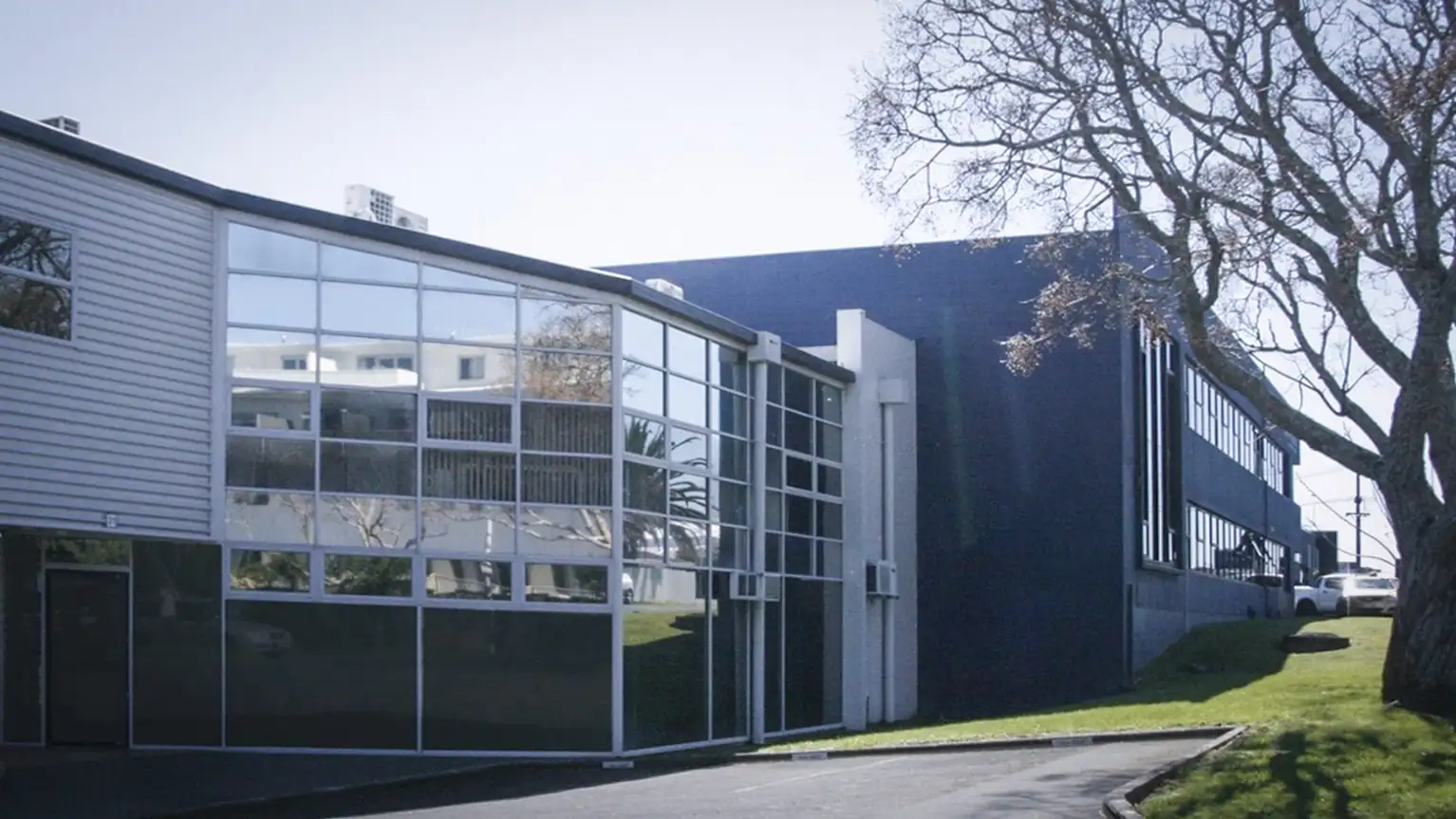 Edificio moderno de oficinas con fachada de vidrio y árboles alrededor.