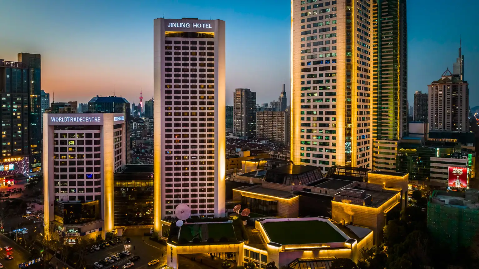 Rascacielos iluminados en el centro de la ciudad al atardecer con el hotel Jinling y el World Trade Centre.