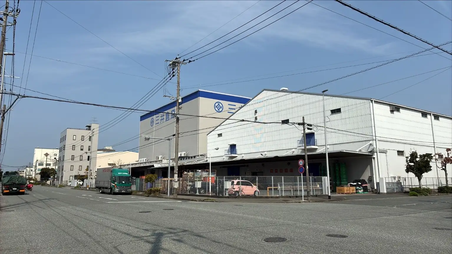 Fábricas y almacenes industriales junto a una calle asfaltada en Japón con camiones estacionados.