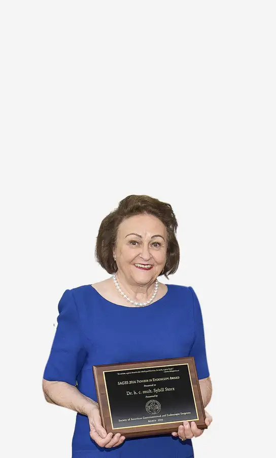 Woman in a blue dress holding an award plaque and smiling at the camera.