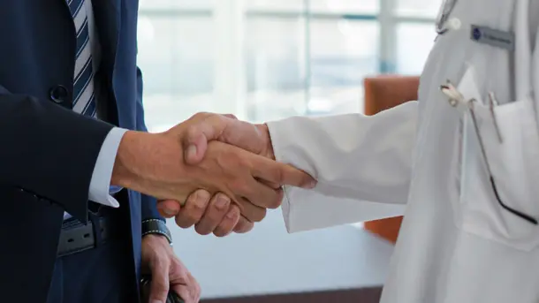 Businessman shaking hands with a doctor in a professional agreement.