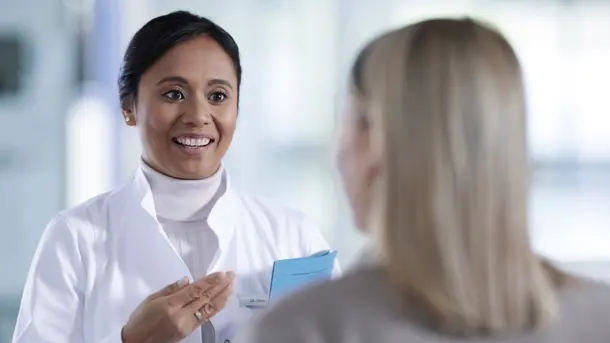 Female doctor discussing medical results with a patient in a clinical setting.