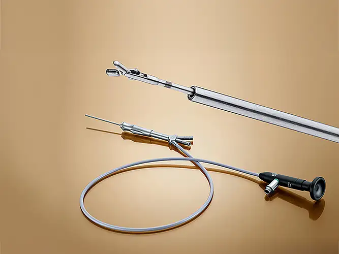 Instrumental médico para endoscopía sobre fondo beige, incluyendo pinzas y cable óptico.