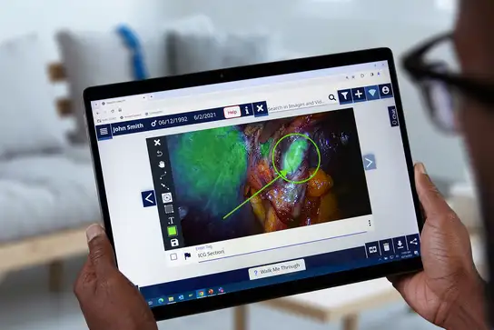 Person viewing a surgical image with highlighted section on a tablet screen.
