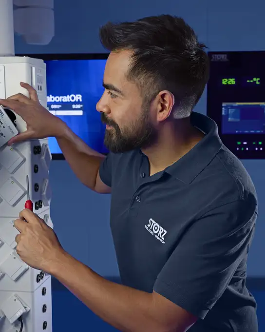 Technician in a polo shirt using a screwdriver to service medical equipment.