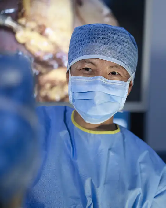 Surgeon in blue scrubs and cap during an operation.