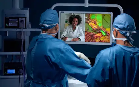 Surgeons in an operating room consult a remote doctor via video call during a surgical procedure.