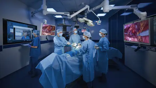 Surgeons performing an operation in a high-tech operating room with advanced medical monitors.