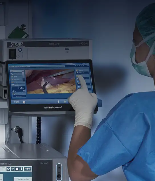 Medical professional interacting with surgical touchscreen monitor during a minimally invasive procedure.
