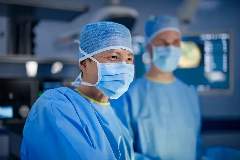 Surgeon wearing a mask and surgical gown during an operation.