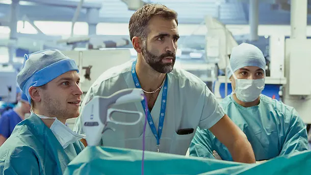 Surgeons in scrubs performing a medical procedure in an operating room.