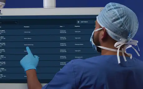 Doctor in surgical cap using a touchscreen medical record system.