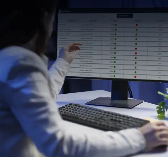 Person operating a computer while viewing a device status monitoring dashboard on the screen.