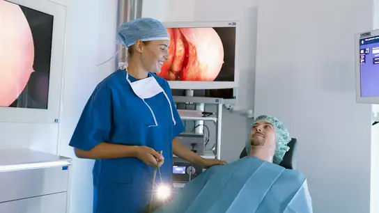 Doctor in surgical attire preparing a patient for an endoscopy procedure.