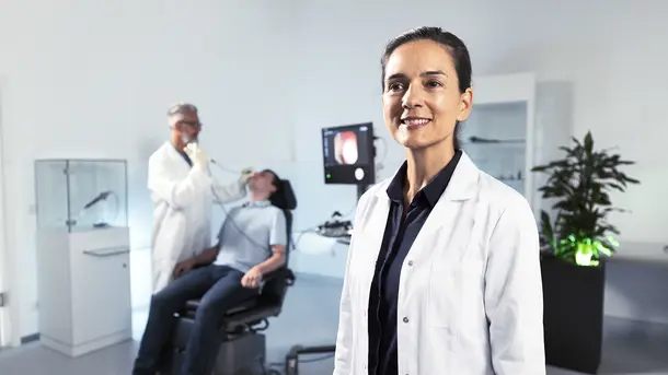 Female doctor in white coat smiling in a modern medical clinic.