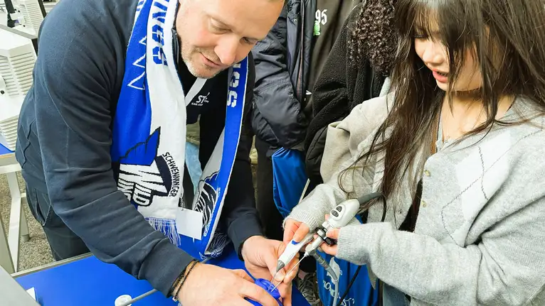 Ein Mann und eine junge Frau benutzen gemeinsam ein technisches Gerät bei einer Vorführung.