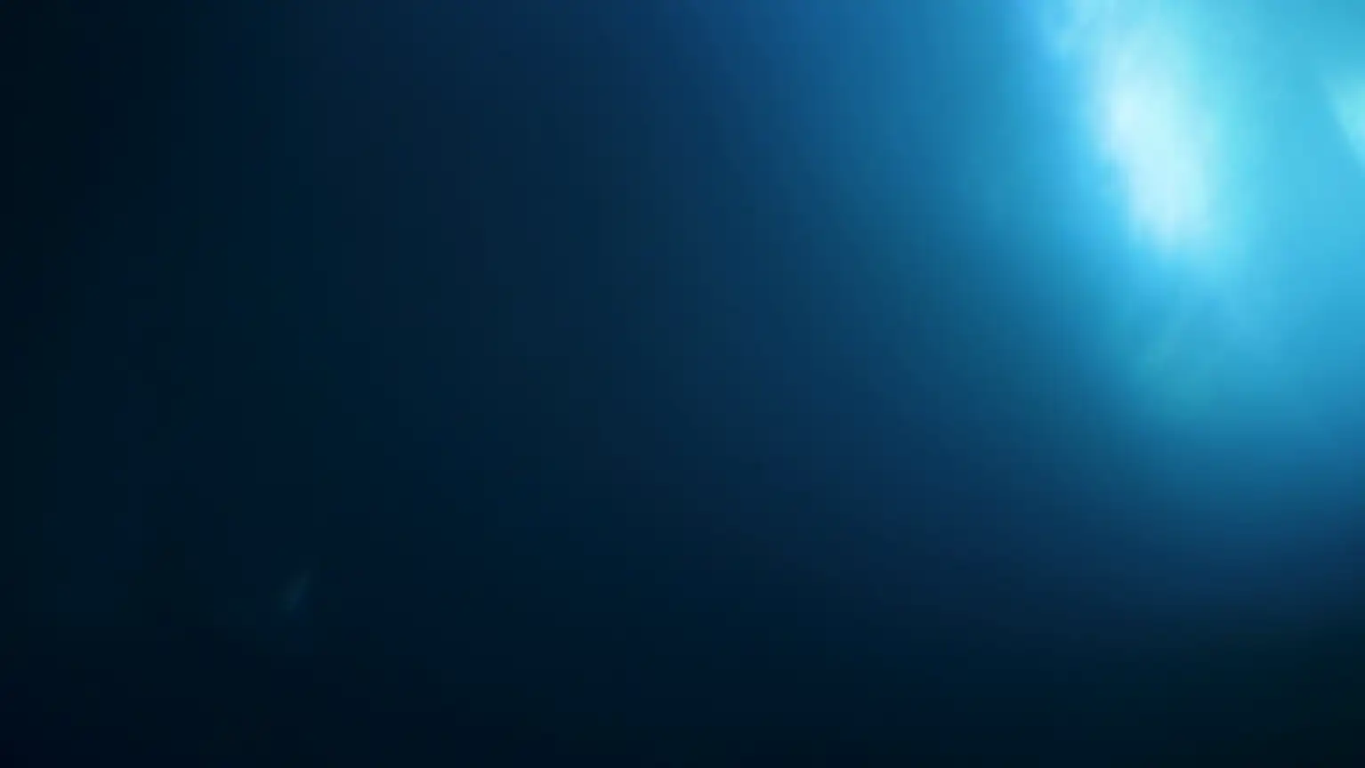 Underwater sunlight shining through the surface, illuminating the deep blue ocean.